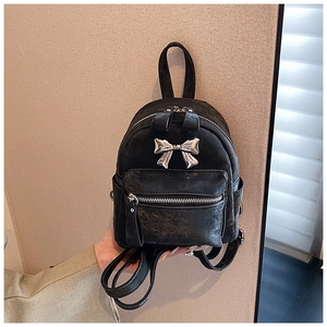Détail d'un mini sac à dos noir en cuir vintage orné d'un nœud décoratif en métal 3D