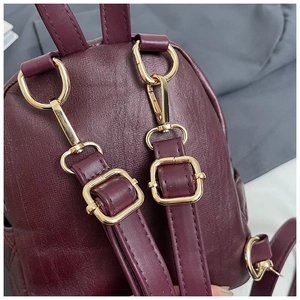 Dettaglio dello zaino in pelle bordeaux con spallacci regolabili e ganci in metallo dorato