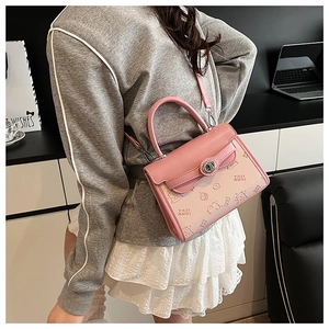 Detailed look at light pink handbag with cartoon bear prints and metal twist lock
