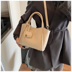 Creamy beige pebbled leather bucket bag featuring a cute elephant charm and strap