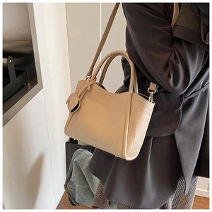 Detail view of beige leather bucket bag with lychee texture and heart-shaped charm