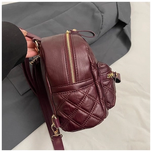 Dettaglio dello zaino mini bordeaux trapuntato con cerniera dorata e texture in pelle