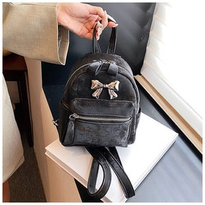 Détail d'un mini sac à dos noir avec nœud en métal argenté et texture simili cuir craquelé