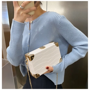 Detail of white crocodile texture box bag with gold metal corners and chain strap