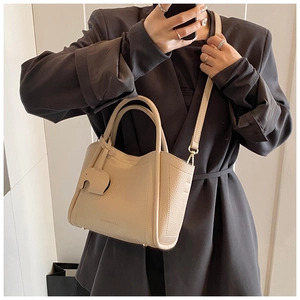 Detail of cream beige pebble leather bucket bag with elephant charm and logo imprint