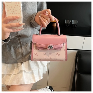 Detail of pink contrast leather handbag featuring a rotary lock and teddy bear motifs