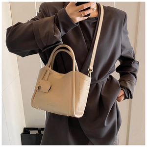 Mirror selfie showing large apricot pebbled leather tote bag with elephant charm and strap