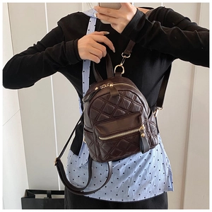 Dettaglio mini zaino trapuntato marrone scuro con finiture dorate su modella donna