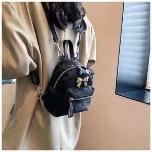 Détail d'un mini sac à dos noir avec nœud métallique et texture porté par un mannequin