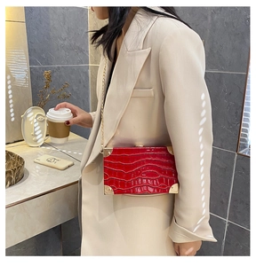 Close-up of red crocodile pattern box bag with gold chain strap worn by a fashion model