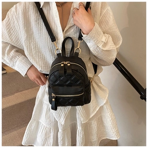 Dettaglio mini zaino trapuntato nero con zip dorate indossato con abito bianco