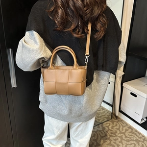 Brown woven crossbody bag with mini square design and leather strap shown on a model