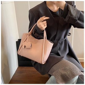 Detail of pink pebbled leather bucket bag with a cute elephant charm accessory