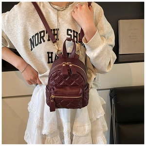 Detail eines burgunderroten Mini-Rucksacks mit Rautensteppung und goldenen Beschlägen