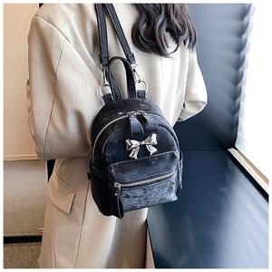 Gros plan d'un mini sac à dos en velours noir avec un nœud métallique sur un mannequin