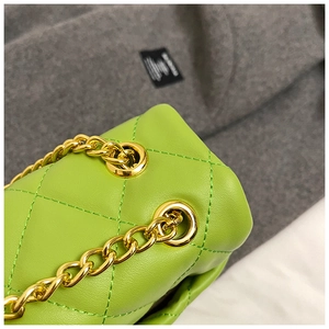 Detailed close-up of green quilted leather bag with golden metal chain and eyelets