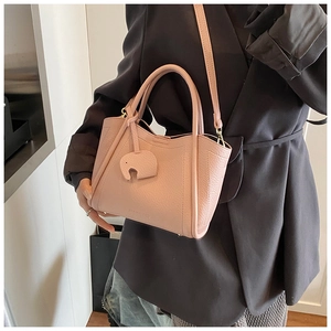 Detail view of pink leather bucket bag featuring a cute elephant charm and pebble texture