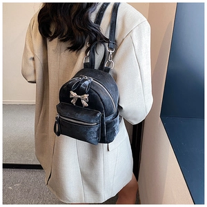Détail d'un mini sac à dos en velours noir avec un nœud argenté et fines bretelles