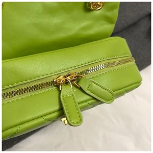Detail of green quilted bag showing golden double zipper closure and precise stitching