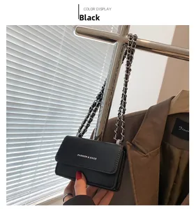 Dettaglio di una mini borsa nera a tracolla con catena e scritta bianca alla moda
