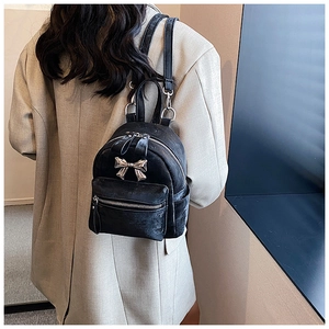 Vue arrière d'un mini sac à dos noir avec un nœud chic et des bretelles en cuir