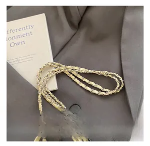Close-up of woven silver metal chain strap with beige leather detail on a suit fabric