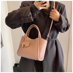 Detail of lychee textured leather bucket bag in apricot pink with elephant charm