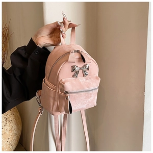 Détail d'un mini sac à dos rose avec texture velours et nœud en métal argenté