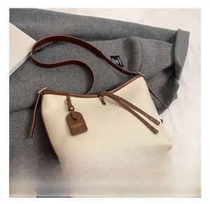 Détails du sac cabas en cuir beige avec garniture marron et pieds de protection dorés