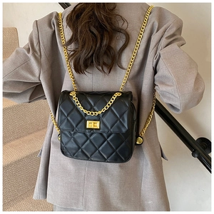Close-up of black quilted chain backpack with gold hardware on a model's back