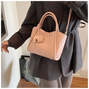 Detail of pink lychee leather bucket bag with cute elephant charm and chic logo
