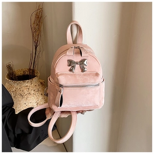 Détail de mini sac à dos rose avec texture velours et nœud doré dans un cadre chic