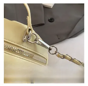 Close-up of silver metal hooks and chain strap on a beige quilted rhombic pattern bag