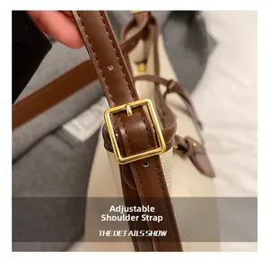 Détail de la bandoulière réglable en cuir marron avec boucle dorée sur un sac fourre-tout