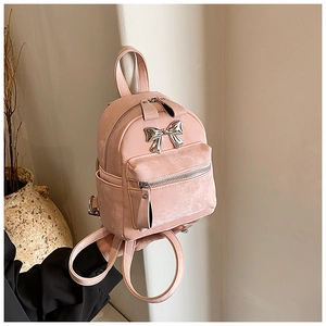 Vue détaillée du mini sac à dos en daim rose avec nœud argenté et poche frontale zippée