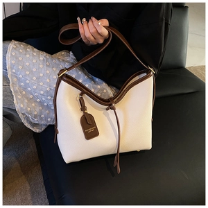 Détail du sac cabas en cuir grainé blanc avec bordures brunes et étiquette mode