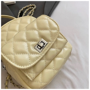 Detail of quilted leather backpack with silver twist lock and chain strap in cream