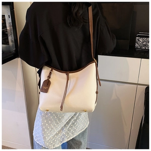Détail du sac à main blanc en cuir grainé avec bordure brune et pieds de protection