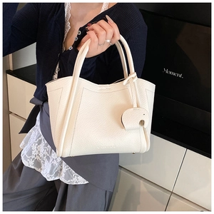 Close-up of cream textured leather bucket bag with brand logo and cute elephant charm