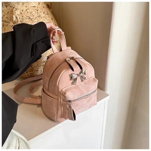 Vue détaillée d'un mini sac à dos rose avec nœud métallique argenté et texture suédée