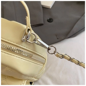 Detail shot of yellow quilted leather handbag with silver metal zippers and chain strap