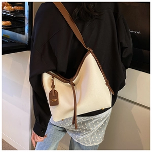 Détail du cabas en cuir crème avec bandoulière large marron et finitions contrastées