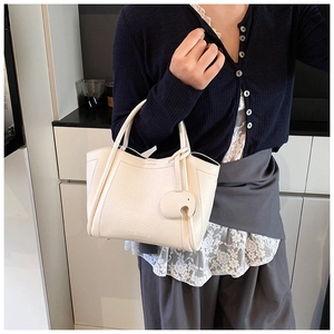 Detail of cream white leather bucket bag featuring elephant charm and brand logo