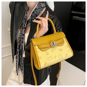 Detail view of yellow printed crossbody bag with cute graphics and silver twist lock