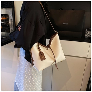 Vue latérale d'un grand sac cabas en cuir beige avec finitions marron sur mannequin