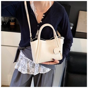 Detail of white lychee leather tote bag with elephant charm and adjustable strap