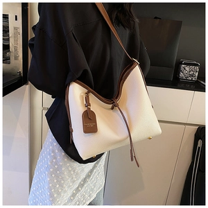Détail du grand sac cabas en cuir grainé crème avec bandoulière marron porté par un mannequin