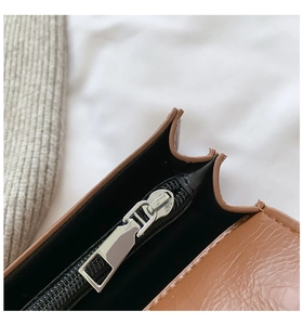 Dettaglio borsa in pelle marrone con trama litchi, zip in metallo argento e fodera nera