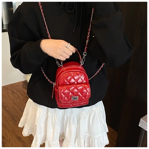 Detailed view of a red quilted mini backpack with silver metal chain and twist-lock pocket