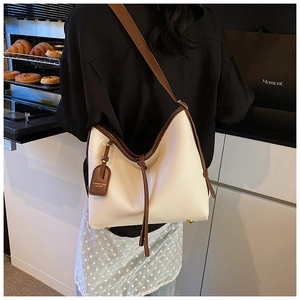 Détail du sac cabas crème avec anses marron contrastées et texture cuir dans une cuisine